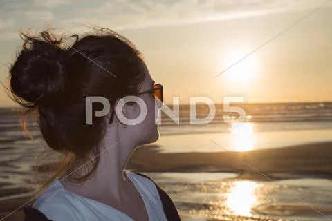 Profile of a woman silhouette watching sun on the beach at sunset Stock Photos