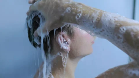 Profile of a young man cleaning his hair with foam in the home shower. Stock Footage 345531268