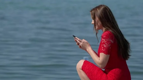 Profile of a young woman using a smart phone on the beach Stock Footage 186587404