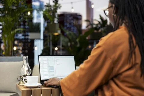Program developer types binary code on laptop from rooftop sofa Stock Photos