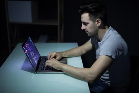 Program development concept. Young man working with computer in the dark Stock Photos
