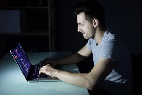 Program development concept. Young man working with computer in the dark Stock Photos