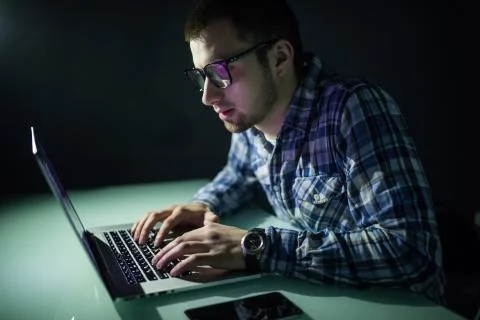 Program development concept. Young man working with computer in the night. Foto stock
