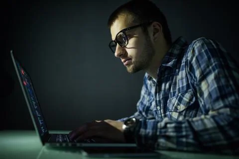 Program development concept. Young man working with computer in the night. Stock Photos