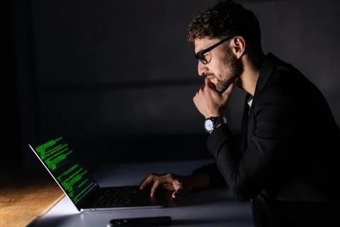 Program development concept. Young man working with computer in the night 库存照片