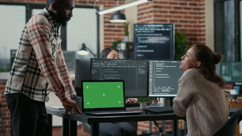 Programer working at desk with multiple computer screens and laptop with green Stock Footage 168251971