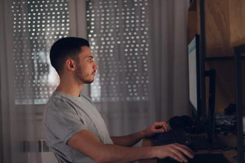 Programer working on his computer while the screen light reflects on his face Stock Photos