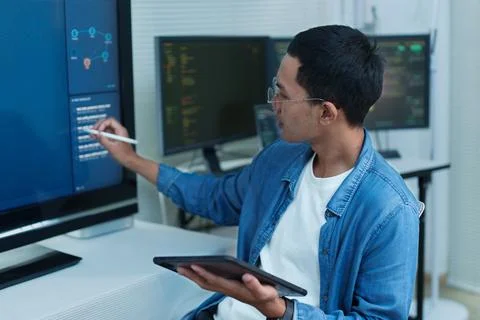 Programmer Analyzing Code on Multiple Screens Stock Photos