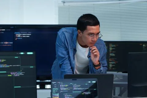 Programmer Analyzing Code on Multiple Screens Fotos Stock