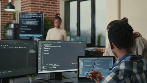 Programmer analyzing compiling code on multiple screens takes off glasses and Video stock 168236126