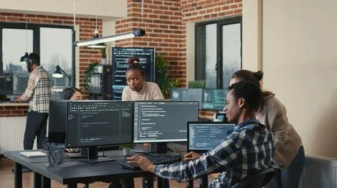Programmer analyzing compiling code on multiple screens takes off glasses and Stock Photos