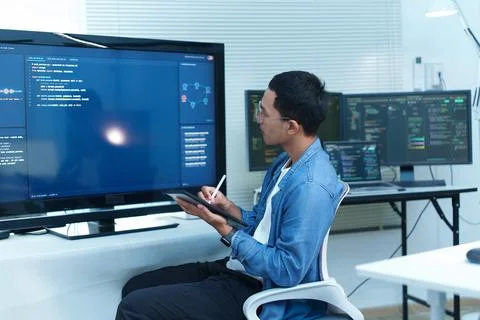 Programmer Analyzing Software Code on Multiple Screens Fotos Stock