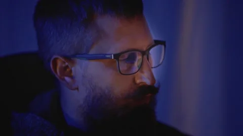 Programmer with a Beard and Glasses Sits in a Dark Room Behind a Monitor. 스톡 동영상 302725032