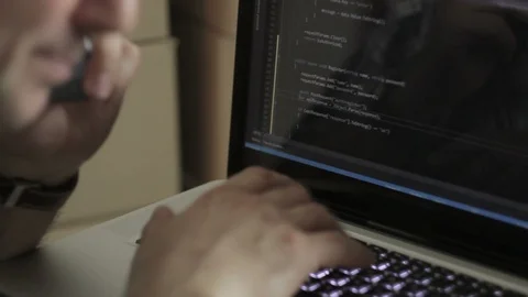 Programmer behind the laptop keyboard. Close-up face with smartphone Stock Footage 86659345