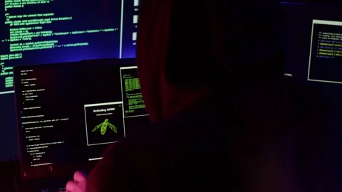 A programmer in a black hoodie hacks a website Stock Footage 194781543
