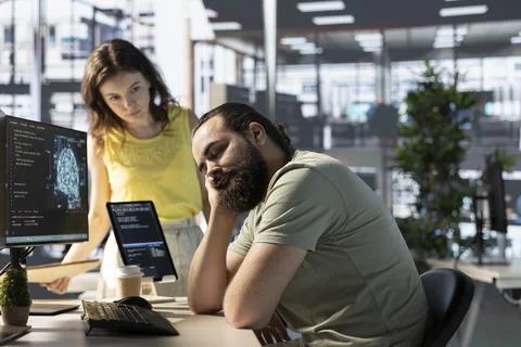 Programmer caught asleep at desk by manager while developing AI Stock Photos