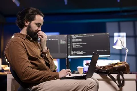 Programmer checking code displayed on computer monitors using laptop 스톡 사진