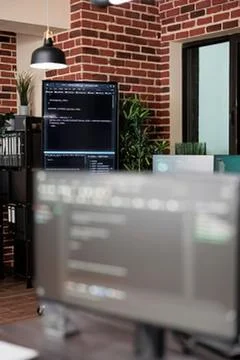 Programmer coding on dual monitors in cozy office Stock Photos