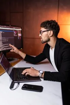 Programmer coding on a laptop in the dark with a view of the lights of the ni 写真素材