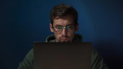 Programmer coding on laptop with focused expression Stock Footage 303998384