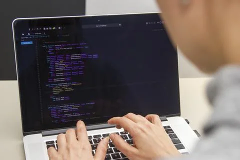 A programmer coding on a laptop in the workplace Stock Photos