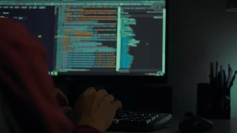 A programmer coding late at night in a dimly lit workspace surrounded by tec 스톡 동영상 288633822