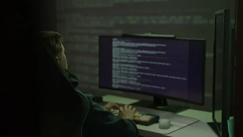 Programmer coding late at night, typing on keyboard with code reflecting on dark Stock Footage 325711675