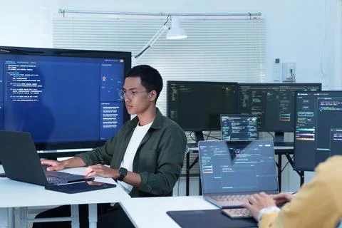 Programmer Coding with Multiple Monitors in Modern Software Office Stock Photos