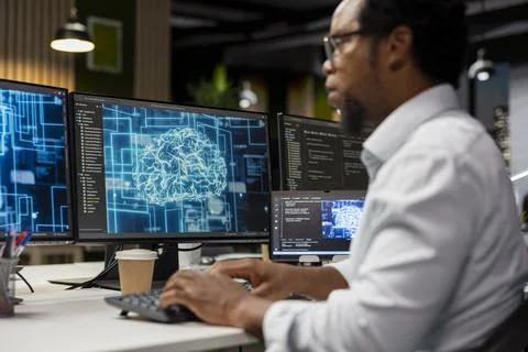 Programmer coding on PC in startup office, refining neural networks tech Stock Photos