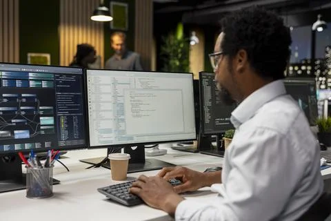 Programmer coding on PC in startup office, refining machine learning models 写真素材