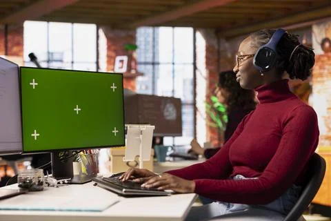 Programmer coding in startup office using isolated screen PC, listening music Stock Photos