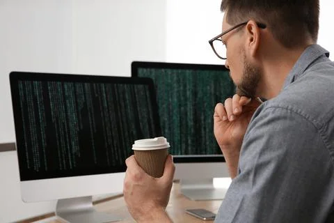 Programmer with coffee working at desk in office Foto stock