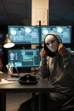 Programmer with concealed identity sitting in dark office room Stock Photos