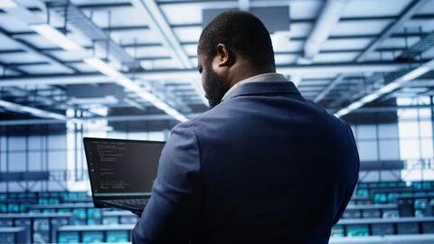 Programmer in data center doing yearly maintenance checkup using laptop 스톡 사진