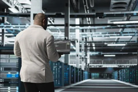 Programmer in data center typing on laptop, writing lines of code Foto stock