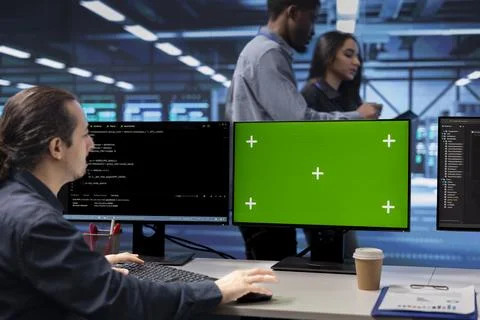 Programmer in data center using green screen computer to check server issues Stock Photos
