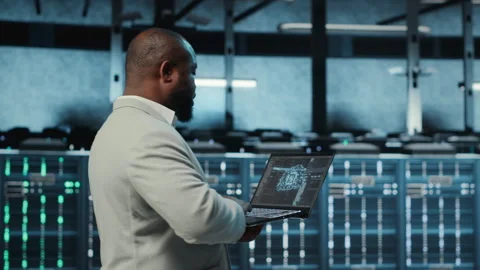 Programmer in data center using laptop, employing AI machine learning models Stock-Footage 311897813