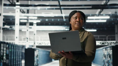 Programmer in data center using laptop to deploy new server architecture Stock-Footage 317124628