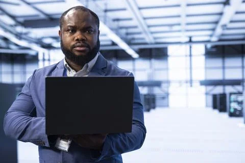 Programmer in data center using laptop to identify and solve technical issue Stock Photos