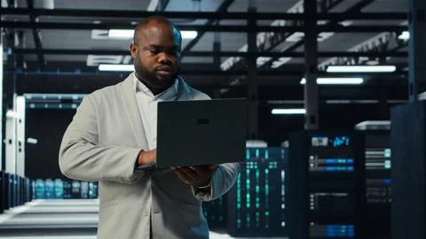 Programmer in data center using laptop, testing equipment failover scenarios Stock Photos