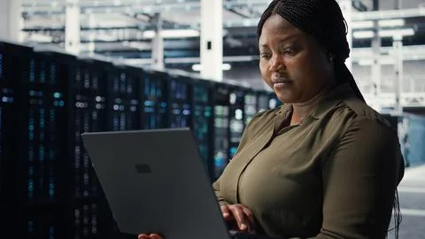 Programmer in data center using laptop to deploy new server architecture Foto stock