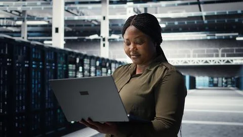 Programmer in data center using laptop to upgrade systems Foto stock