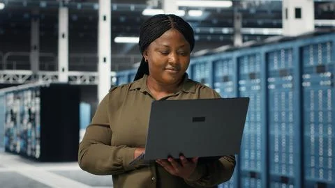 Programmer in data center using laptop to upgrade systems Foto stock