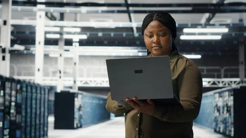 Programmer in data center using laptop to deploy new server architecture Foto stock