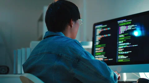 Programmer debugging software code on multi-monitor setup at night in modern Stock Footage 313813631