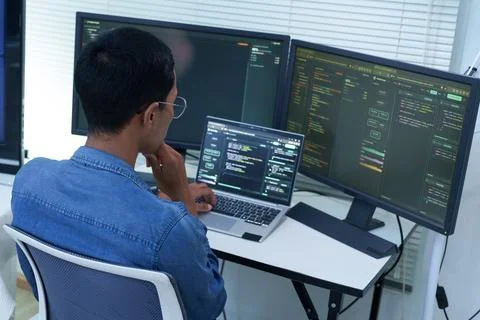 Programmer Developing Software with Code on Multiple Screens Stock-Fotos