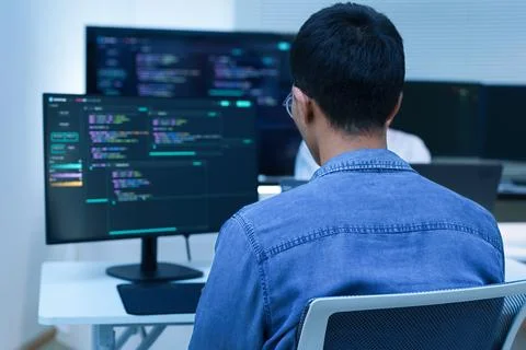 Programmer Developing Software with Code on Multiple Screens Stock Photos
