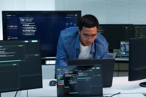 Programmer Developing Software with Code on Multiple Screens Fotos Stock