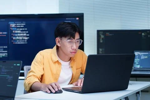 Programmer Developing Software with Code on Multiple Screens Fotos Stock