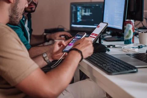A programmer diligently testing smartphone applications while sitting in their Stockfoto's